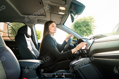 Preview: Businesswoman in black suit sits behind the wheel of a premium car and looks the way looking at the