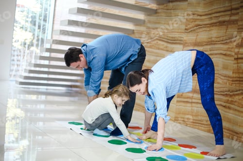 Preview: kids with father and mother playing twister game at home. Family activity