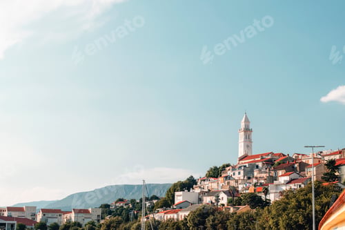 Preview: Village with red roofs and white church tower under clear blue sky. Novi Vinodolski town, Croatia