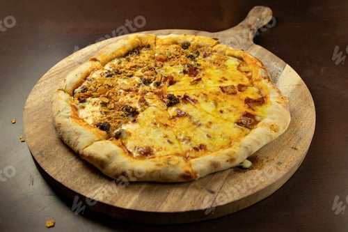 Preview: Closeup of a whole pizza with melted cheese and meat on a wooden board on the table