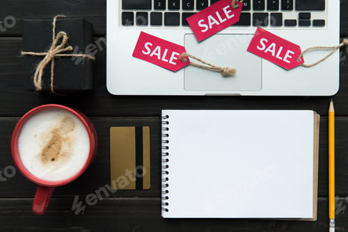 Preview: top view of laptop on table with coffee, credit card, notepad and sale tags