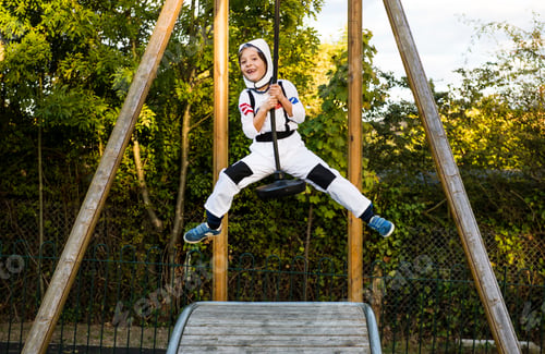 Preview: Portrait of boy in astronaut costume riding on playground zip wire