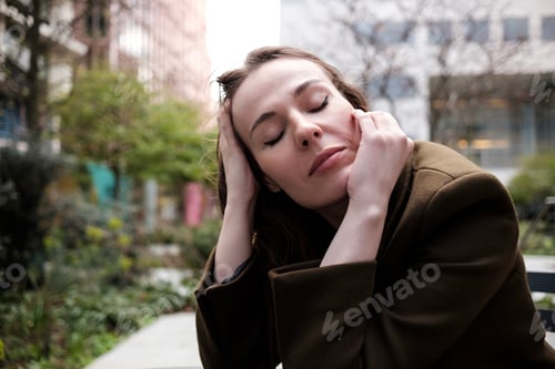 Preview: Portrait of relaxed woman with eyes closed sitting on table outdoors.