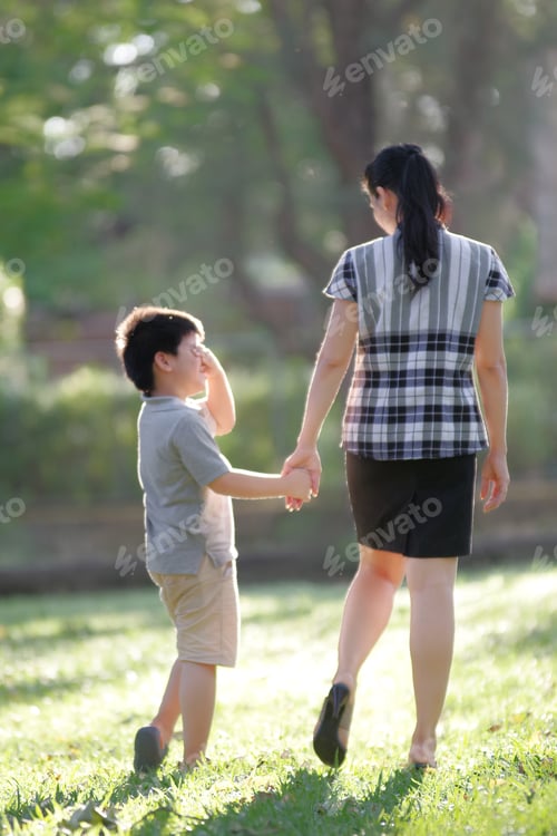Preview: Mother and son walking hand in hand in the backyard on a sunny day