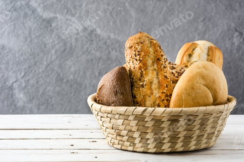 Preview: Wicker basket overflowing with various bread loaves on white table