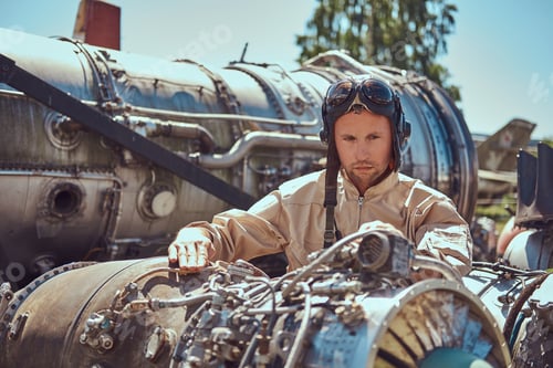 Preview: Mechanic in uniform repairing the dismantled airplane turbine in an open-air museum.