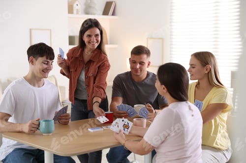 Preview: Group of friends playing cards at wooden table indoors
