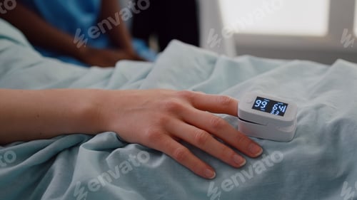 Preview: Close up of hospitalized woman with finger heart rate monitor showing pulse