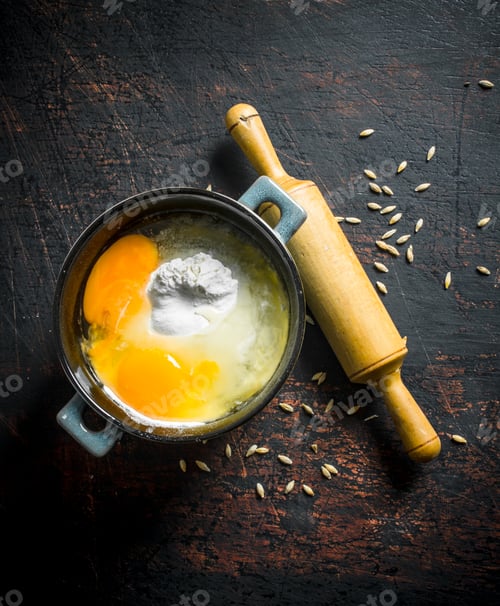 Preview: Flour with eggs in a pan with a rolling pin and grain.