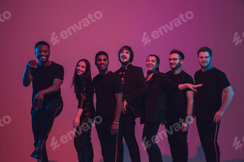 Preview: Group of young multiethnic musicians created band, dancing in neon light on pink background