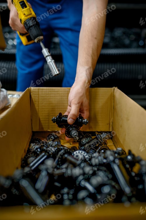 Preview: Worker in uniform at the box with bicycle hubs
