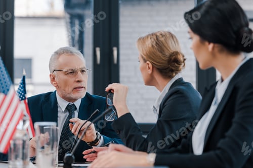 Preview: selective focus of bearded businessman looking at attractive diplomats