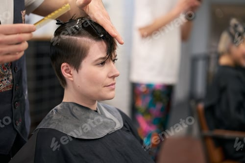 Preview: Hairdresser combing and cutting hair of young female model in salon