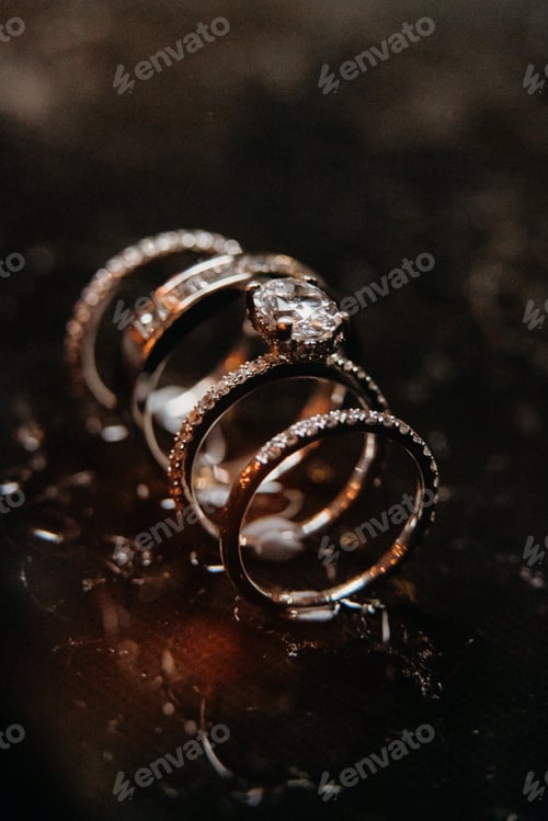 Preview: close up of two gold wedding rings set on top of a dark marble surface