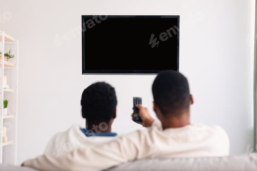 Preview: Black couple watching TV with mockup and using remote controller
