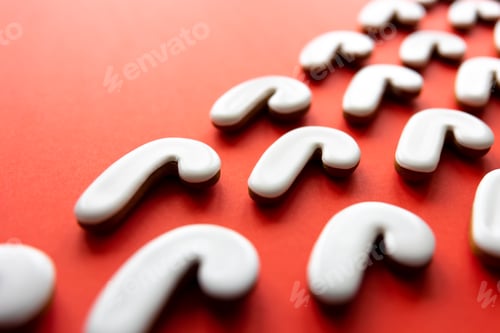 Preview: A lot of gingerbread candy cane shaped cookies on a red background.