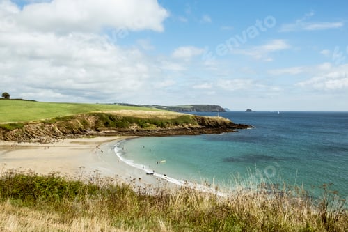 Preview: View over a sandy beach and cliffs in summer, a few people, clear shallow water and calm sea.