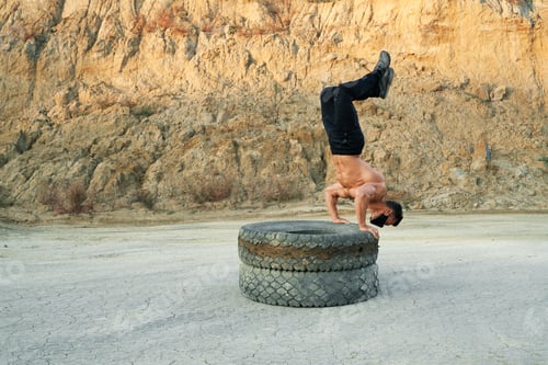 Preview: Active guy balancing on tyres while training outdoors
