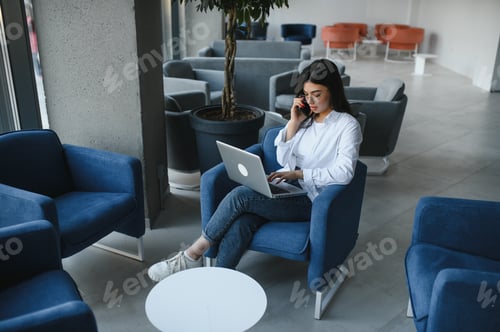 Preview: Woman Works on Laptop, Talking on Mobile Phone