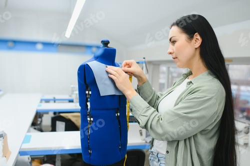 Preview: Portrait of a beautiful seamstress carrying a tape measure and working in a textile factory