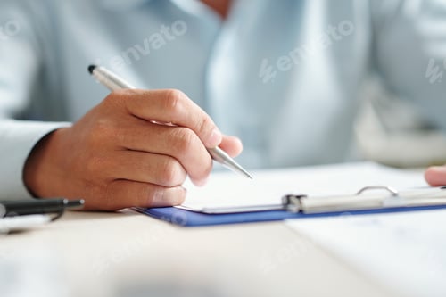 Preview: Person Holding Pen Over Paper on Clipboard