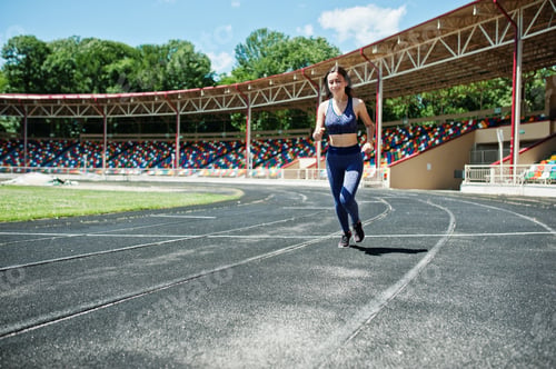 Preview: Portrait of a strong fit girl in sportswear running in the stadium.