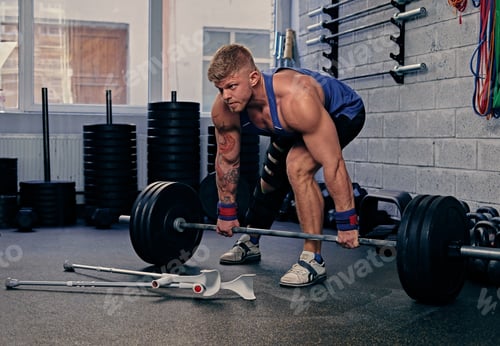 Preview: Bodybuilder with injured leg holds barbell.