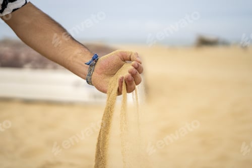 Preview: Closeup of sand running through a man's hand - concept of time