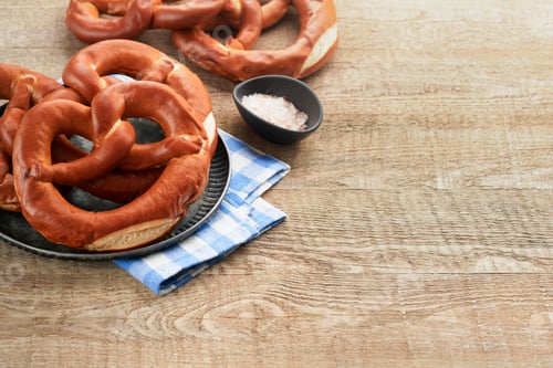 Preview: Oktoberfest concept card. Traditional Bavarian pretzels with beer bottle mug on old rustic wooden ba
