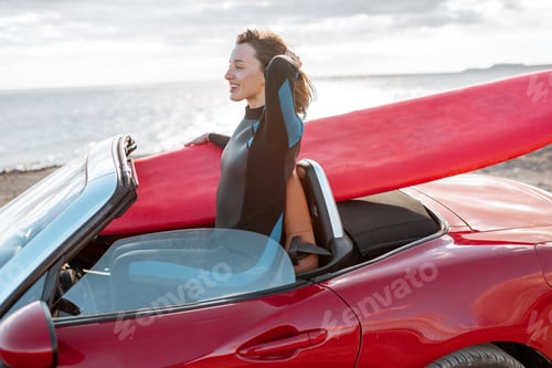 Preview: Woman with surfboard on the car near the ocean
