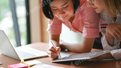 Preview: Asian female graphic designer working together at the office They use laptop and tablet.