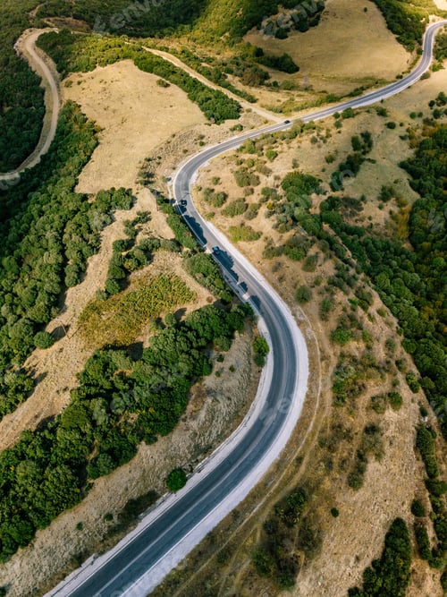 Preview: Aerial above view of a rural landscape with a curvy road running through it in Greece.
