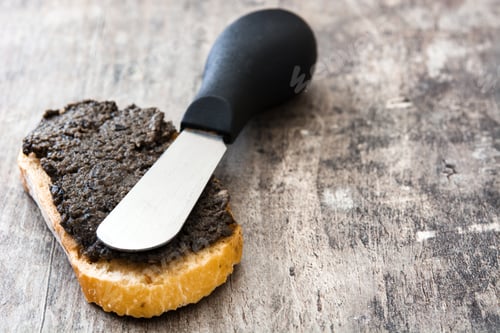 Preview: Spreading black olive tapenade on bread with a knife