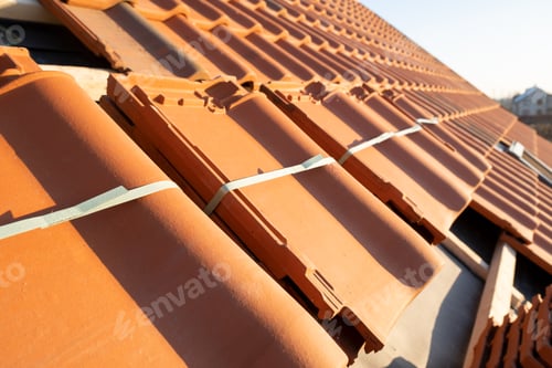 Preview: Stacks of yellow ceramic roofing tiles for covering residential building roof under construction.
