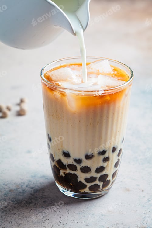 Preview: Milk bubble tea with tapioca pearls in glass, gray background.