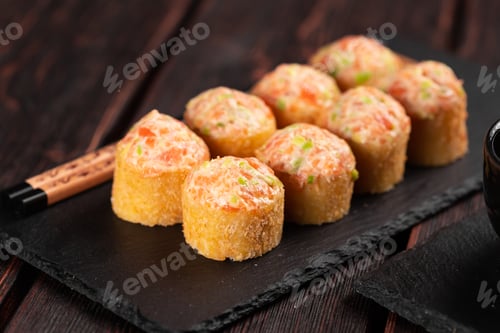 Preview: Sushi roll with mayonnaise sauce served on black board and soy sauce.