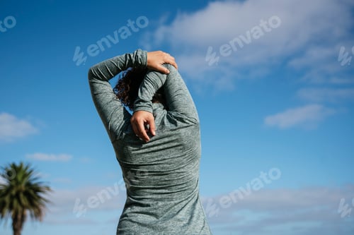 Preview: young woman stretching shoulders in nature