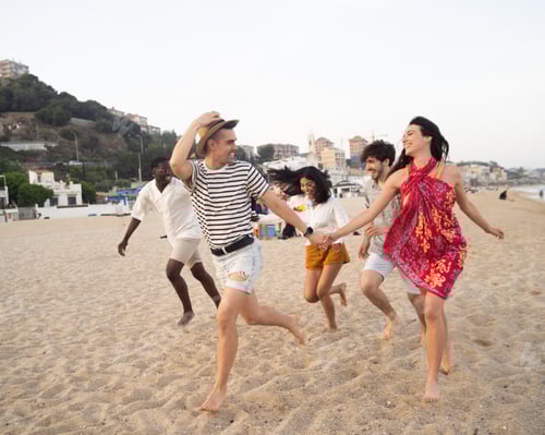 Preview: Group of young friends happily running on the beach during summer vacation