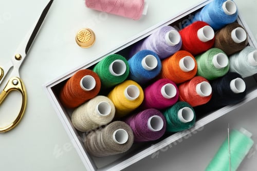 Preview: Box with colorful sewing threads, scissors and thimble on white marble table, flat lay
