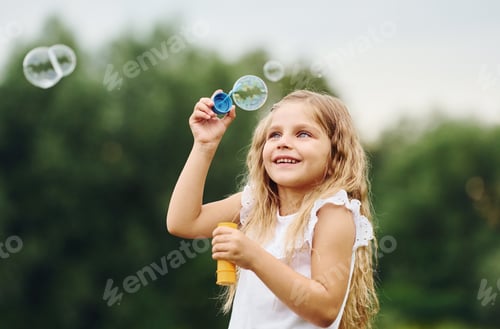 Preview: Little girl is playing with bubbles outdoors