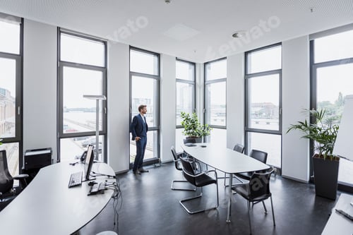 Preview: Businessman standing in his office looking out of the window