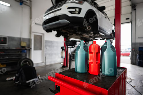 Preview: Car maintenance in garage with motor oil bottles in foreground