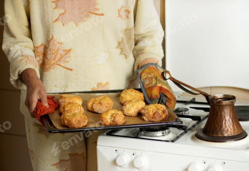 Preview: Woman holds baked cheese breads for breakfast in a baking tray and Turkish coffee at the oven