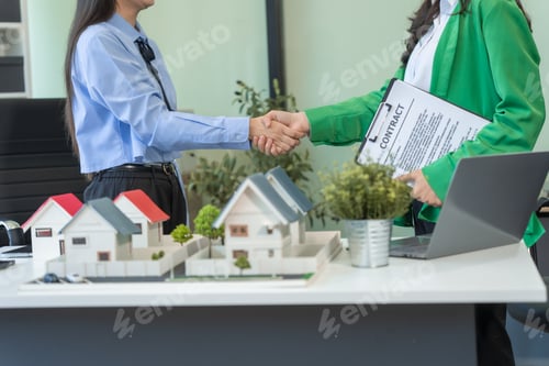 Preview: Two businesswomen sit at a table in the office,discussing a model village with windmills
