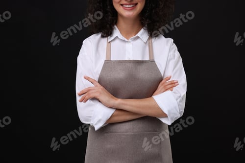 Preview: Woman wearing kitchen apron on black background, closeup. Mockup for design