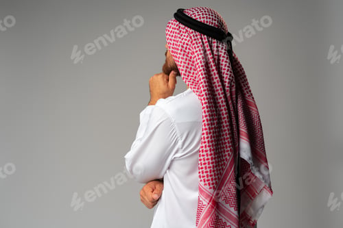 Preview: Back view of young Arab man standing on gray background
