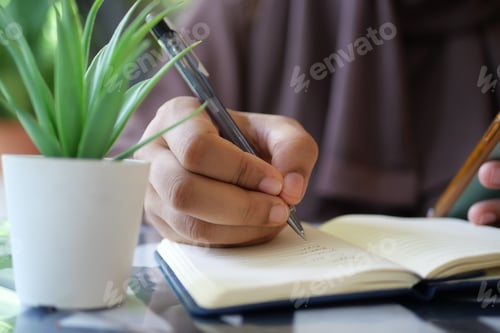 Preview: Close up of women hand writing on notepad.