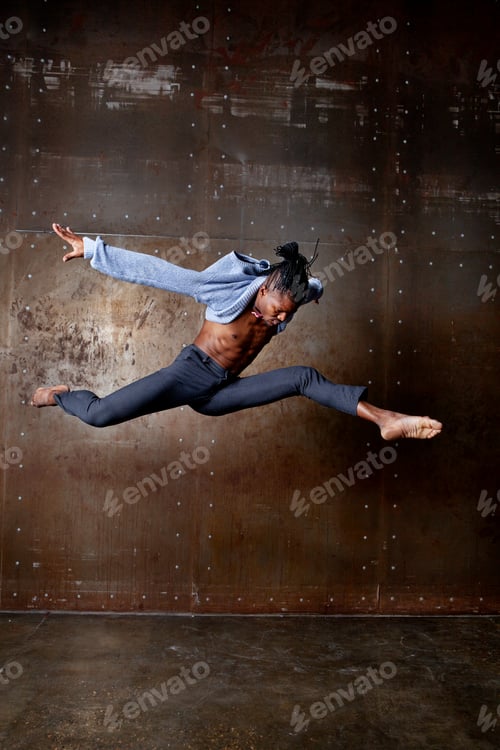 Preview: Energetic Afro American male dancer jumps and twirls in studio. Black man dancing indoors