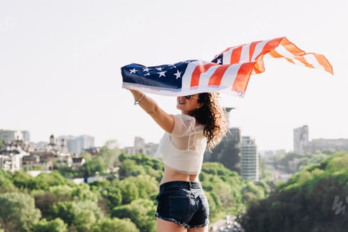 Preview: Woman Holding Flag in Urban Landscape on Sunny Day