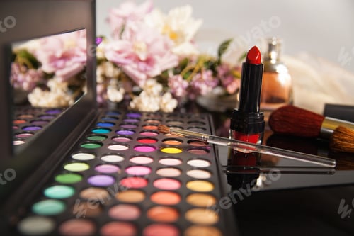 Preview: Colorful eye shadow palette and a red lipstick with flowers in the background